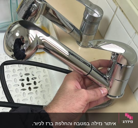 יד מחזיקה ברז נשלף בכיור מטבח